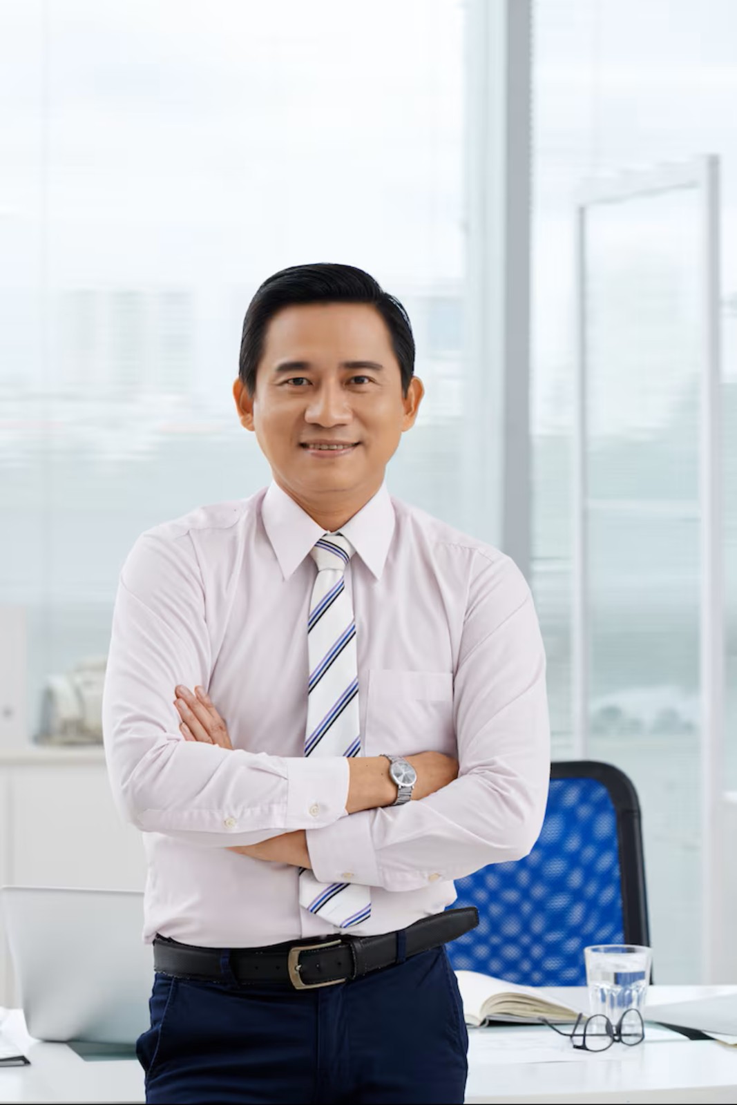 Professional portrait of a man wearing a gray suit, white shirt, and purple patterned tie, standing against a gray background.